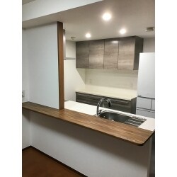 キッチンとリビングの間の壁をなくし、LDKとして一体感のある空間を作り出しました。
また、吊戸棚もなくしたことで開放的な対面キッチンとなりました。