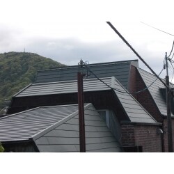 雨漏れと見栄えの悪さをなおしたいとのご要望でした。
お家自体が建築家の方が元々設計されて住まわれていたものを中古物件でご購入され、見栄えはいいもののメンテナンスが大変なので手のかからないものがご希望でした。

既存の屋根はシングル材で劣化も激しくところどころ捲れてしまっている状態でした。
シングル材は補修が難しい材料なので、見た目の近い金属屋根のカバー工法をご提案しました。
日鉄鋼板のアポロルーフを使用し煉瓦の外壁と屋根のバランスを保つことができました。

メンテナンスのしやすさも加わりお客様にも喜んでいただくことができました。

