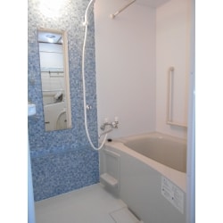 リフォーム完成後の浴室の写真です。
浴槽横にL型の手摺り、ドア横の壁にI型の手摺りがそれぞれ付いています。
アクセントのブルーのタイルが印象的。（標準仕様です）