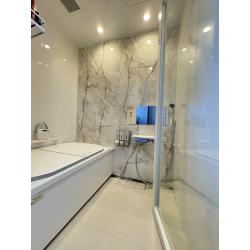 浴室の壁の一面には、グレーとゴールドの脈模様が美しい「大理石調のアクセントパネル」を採用。他の壁を清潔感のある白にすることで、パネルのデザインを際立たせつつ、圧迫感のない広々とした空間を演出しています。