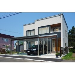角地に面した敷地に奥行と立体感を持たせるプランを想像しました。当初は2台用カーポートでの設置予定でしたが、梁を延長させることによってアプローチにゲートを設け、導線をハッキリと強調しています。またカーポートとフェンスのカラー・木彫を玄関ドアと統一させ一体感を演出しています。ライトアップはカーポート部分だけですが、夜のお庭もまた素敵に仕上がっています。