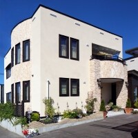 優しい風合いの塗り壁に石調タイルが映える外壁