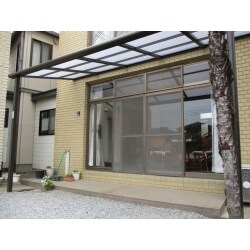 屋根材に網入りガラスが使用してあった鉄骨製テラスを解体して、アルミ製テラスを取り付けました。間口（柱から柱までの寸法）は、４ｍ５０ｃｍで出幅が１ｍ８０ｃｍと広々としたテラスが完成しました。リビングに差し込む“太陽光”を和らげるために、半透明の屋根材を採用しました。
