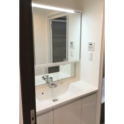 施工前の洗面化粧台は、古くなり落ちない汚れなどが目立ってきたとお悩みでした。鏡の両脇に設置された丸見えの収納スペースを隠したいのと、横幅が大きな洗面台へ交換したいとのお客様のご要望。三面鏡の収納スペースや洗面下の収納もたっぷりありご満足いただいております。壁紙や洗面化粧台をホワイトへ統一し、清潔感あふれる洗面スペースとなりました。