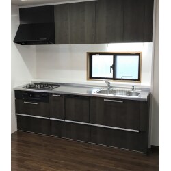 壁付きＩ型システムキッチン。施工前のナチュラルな雰囲気とは変わり、ダーク系のブラウンでスッキリとしたスタイリッシュな雰囲気になりました。大容量の収納スペースを設け、使いやすい引き出し式収納へ、デザインも機能も充実しています。シンクも広々、汚れにくいシステムキッチンへ交換しました。