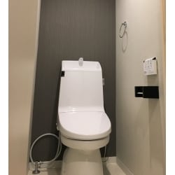 トイレ室内の雰囲気がお客さまのイメージと異なっていたためリフォームをされました。LIXIL　アメージュ　シャワートイレへ交換。広く深く使用しやすい手洗い鉢がついています。汚れにくくお掃除しやすい機能も充実！ホワイトのトイレに、スタイリッシュな壁紙を合わせ、すっきりとしたデザインになりました。