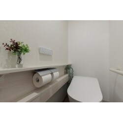 現場調査にお伺いした際、トイレの収納ラックやタオルバーに観葉植物が添えられているのを見て、グリーンを好まれていることが伝わってきました。そこで、トイレの背面・手すり側・入口側の３面には白地クロス、カウンター側はアクセントとなるように、淡いグリーンの地にやわらかなリーフ模様が描かれたクロスをご提案。
一見すると無地のように見えるメインの壁紙も、光の加減でコテ塗りのような風合いが浮かび上がり、おしゃれな雰囲気のトイレとなりました。