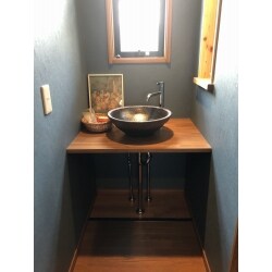 二階の廊下にある洗面化粧台を、雰囲気のある洗面コーナーとなるよう造作しました。黒く光沢のある信楽焼の洗面ボウルとブルーグレーの壁が上品でモダンな空間に仕上げています。
