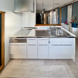 IHシステムキッチンは、LIXIL「ノクト」へ刷新。
ステンレスワークトップ、IHコンロ・レンジフードもステンレスで統一し、洗練された美しさを演出しています。扉カラーとエンドパネルには白を採用し、全体の印象を軽やかにまとめました。

床には石目調のクッションフロアを合わせ、今回の施工全体のメインカラーであるステンレスや石目模様のグレーと調和。既存のお部屋のデザインに自然になじみながら、シンプルで都会的な雰囲気へと生まれ変わりました。