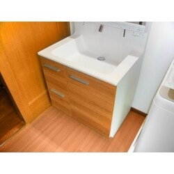 脱衣場の床と壁紙の張り替えと、洗濯機の下には防水パンの設置をご希望でした。また、現在の洗面化粧台の位置を壁に寄せ、同じ幅で同じ収納構成のものに交換したいとのご要望でした。床は耐水性のあるクッションフロアに変更し、床下点検口の新設をご提案しました。洗面化粧台は旧来と同じ収納構成で節湯機能付きの製品を、使い勝手を重視した配置に変更いたしました。