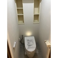 直線を基調としたシンプルで整ったフォルムのタンクレストイレに交換しました。水からつくる安全なきれい除菌水を自動で吹きかけ、便器・ノズル・便座の汚れ、そしてニオイの元になる菌を除菌してくれる機能がついています。便器の表面は汚れが落ちやすい加工が施され、フチなし形状でお掃除がぐっと楽になります。 もともと設置してあった11Lの便器と比べ、56%も節水ができる超節水タイプです。停電時も便器の水を流すことができる安心設計です。タンクレストイレへ交換したことで空間が広く感じるようになりました。クロスは明るい白へ、クッションフロアはモルタル調のグレーに交換し、シンプルなデザインで居心地のいい空間になりました。