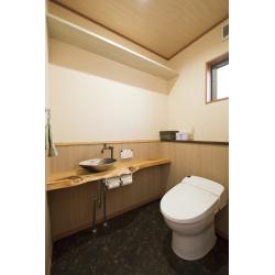木の温もりを感じる和モダンなトイレ空間。無垢材のカウンターと信楽焼風の手洗い鉢が落ち着いた雰囲気を演出しています。自然素材と機能美が調和した癒しの空間です。