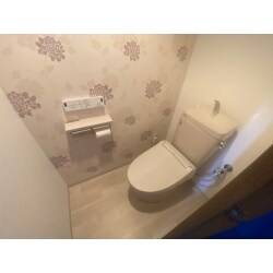 トイレのアクセントクロスは、イギリスの人気ファッションブランド「ローラアシュレイ（Laura Ashley）」のデザインで、フェミニンな花柄を選ばれ、センスの良いオシャレなトイレに仕上がりました。
