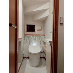 リーフ柄のアクセントクロスが印象的な明るい空間のトイレへ！