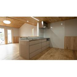 【ナチュラルテイストのオープンキッチン】


木の温もりを感じるナチュラルテイストのLDKに、機能的な対面式キッチンを設置しました。
天井・床・腰壁には天然木を使用し、統一感のある柔らかな雰囲気を演出しています。
キッチンはシンプルなベージュ系のカラーでまとめ、ステンレス天板との組み合わせが清潔感を高めています。
背面の壁にはキッチンパネルを採用し、お手入れがしやすい設計に。
明るい窓から自然光が差し込み、開放感のある空間に仕上がりました。