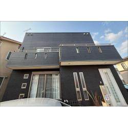白系からダークグレーに塗り替えた、モダンなキューブ型住宅の施工後です。窓周りのひび割れや外壁の色あせ、コケといった経年による傷みをまとめて解消し、印象を大きく一新しています。

外壁にはLuxury無機を使用しました。石材調チップが入った塗料で、塗装後も高級感のある質感に仕上がります。30年耐久・保証15年の高い性能を持ち、家健アフターメンテナンス（定期点検7回）も付いており、長期にわたって建物の状態を確認できる体制が整っています。

外壁全面をダークグレーで統一したことで、建物のシャープなシルエットがより際立ち、施工前とは大きく印象が変わった仕上がりになっています。