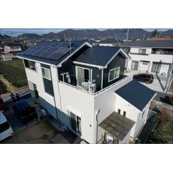 屋根・外壁をまとめて塗り替えた施工後をドローンで撮影した様子です。1階を白系、2階を黒系に色分けしたツートンで仕上がっており、スレート屋根のダーク系と合わさって全体として引き締まったモダンな印象になっています。ソーラーパネルまわりも含めて均一に仕上がっており、白い付帯部との色のバランスもよくまとまっています。

屋根・外壁ともに無機レガロシリーズを使用しました。外壁17年耐久・保証7年、屋根15年耐久・保証5年の性能を持ち、家健アフターメンテナンス（外壁3回・屋根2回の定期点検）も付いており、塗装後の経過を継続して確認できる体制が整っています。