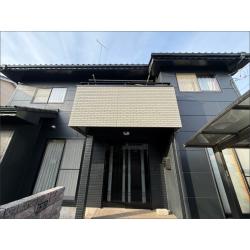 施工後の正面全景です。以前のピンク系の外壁から黒系に塗り替えられ、建物の印象が大きく変わりました。玄関まわりはイノベーションコートで復元施工しており、外壁の黒との対比が落ち着いた雰囲気をつくっています。施工前に確認されたひび割れや塗膜の剥がれも補修済みで、見た目だけでなく防水性もしっかりと回復しています。無機ゼニスシリーズの高耐久塗膜が、これからも建物を長期にわたって守ります。