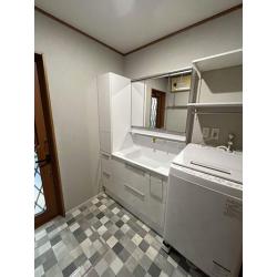 横幅のスペースを最大限に活用し、洗面化粧台とキャビネットを設置。洗濯機上には可動棚を取付たことで、収納力がUPした洗面空間に！さらにホスクリーンを設置したことで、洗濯機からすぐに干せる家事楽同線も実現。床は柄のあるクッションフロアを採用し、設備機器も映える素敵な空間となりました。

