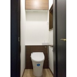 トイレ室内の機器・内装（壁と床）と吊戸棚の交換を行い、トイレ室内の側面と玄関の壁には調湿とニオイをカットする性能に優れた室内用デザインタイル、エコカラットを貼りました。