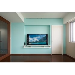 リビングに隣接する個室のリフォームにあわせて、間仕切り壁にテレビコーナーを造作しました。約30cmの壁厚を利用して凹みをつくり、奥行き40cmのカウンターを設置。テレビ端子やコンセントはテレビの背面に移設しています。明るい水色のクロスで仕上げ、リビングの印象が一新されました。隣室工事のタイミングと壁厚を利用した、かしこいリフォームです。