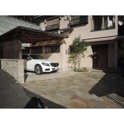 車を止めるところが芝生だったため、土が上がってきたり、水たまりができたりで気になっていたが、なかなか手付かずのところだったそうです。今回は思い切って、乱形の石貼りで見栄えよく玄関までの土間をつくりました。
豪華です。せっかくきれいにするのであれば立ち上がりの隣地境界ブロックも石を張った方が美しく仕上がるので、壁にもベルストーンの石を貼りました。全体的に統一感が出て明るくなりました。