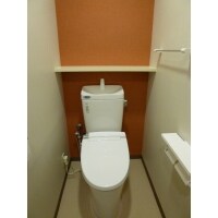 オレンジのアクセントクロスであたたかみのあるトイレ