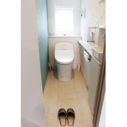 階段下のトイレ。限られたスペースを広く感じる為に、タンクレス風トイレへ取り替え、きれいな色の床材やクロスを選定。おうとつのあるデザインのクロスが光を乱反射してより明るく感じさせます。