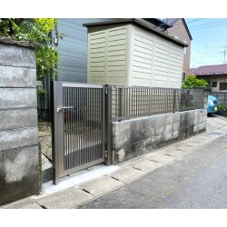 倉庫の屋根からの雨垂れでブロック塀が劣化し、穴が空いているので、綺麗に解消したいとのご要望でした。ブロック塀の上部をフェンスに改修、扉も一緒に交換して主張しすぎない色で統一感のある外構に改修致しました。