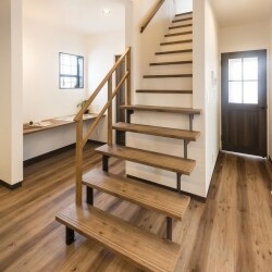 玄関ホールの真ん中に作った階段。家の中心に登りきる事で、廊下を短くすることが出来るので、２階の居室が広く使えるようになります。２階中央のホールから各部屋に行くことが出来るので。