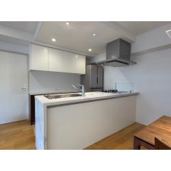 ダイニング側の壁を撤去し、空間を一体化することで、家族が自然と集まる対面キッチンへとリフォームしました。採用したのはPanasonicのLクラスキッチン。開放感のあるレイアウトにより、調理中でも家族の様子を感じられ、会話が生まれやすいキッチンスペースに仕上がっています。カウンターには人造大理石クォーツのレユールホワイト（BQS）を使用。上質な質感と明るい色合いが空間全体を引き締め、ダイニングと調和した上品で心地よい団らん空間を演出しています。