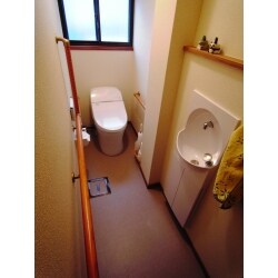 和式トイレから洋式トイレに
小便器のあった場所は埋め込み型の手洗い器を設置。
大便器は奥行の少ない寸法を用いて、中間にある二階排水管の通るパイプスペースの出っ張りを避けています。
手すりを設置してご高齢のお母様の使い勝手に配慮しています。
