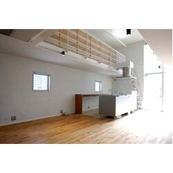 高い天井と窓から差し込む外光の中ひときわ存在感を放つシルバーの無機質なキッチン