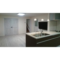 白っぽい木目調の床と建具が温もりを与える室内。そこにキッチンのダーク色のコントラストが空間をモダンに演出しています。