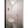 凹凸の少ない、清掃しやすいキャビネット式トイレと内装を白で統一したトイレ空間に、細身の真鍮のペーパーホルダー、タオル掛けが配され、陰影の美しい照明とともに空間を洗練された印象にかえています。

