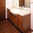 洗面所の扉や収納庫にまで無垢のオークル材を使用。シンプルで清潔感のある空間に、大型の鏡を取り付けて広さを演出しています。