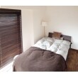 寝室には木製ブラインドを取付。ブラウンの色合いにあわせた無垢フローリングとインテリアでシックな雰囲気に仕上がっています。