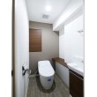 節水性と清掃性を兼ね備えたタンクレストイレに変えることで広々空間を演出。流線的なデザインとコンパクトなフォルムが印象的です。収納扉やカウンターの色を統一する事で、スッキリとした一体感のある空間を目指しました。
