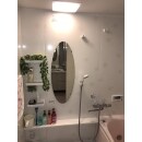 壁面パネルに花柄、丸みのある鏡で入った可愛らしい浴室に