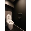 濃厚な黒の壁と柔らかいグレーの壁でシックな仕上がりのトイレ