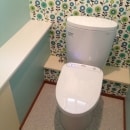 トイレ本体は取替、手洗いカウンターは既設品。奥の壁に特徴のある柄のクロスを採用、周りの壁は色合いを合わせています。