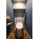 エンボス加工されたネイビークロスと、おしゃれなヘリンボーン柄のクッションフロアで落ち着きのある北欧風のトイレは、奥の壁にアクセントクロスもあしらってかわいさもプラス。