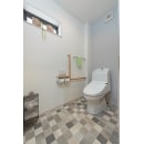 バリアフリー仕様のトイレ。背面壁のアクセントクロスとチェック柄の床材がポイントに。