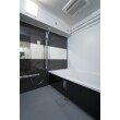 照明は白く明るく、アクセントの黒と床のグレーで高級感のある浴室