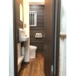狭かったトイレを広くするため、コンパクトなLIXIL『サティスＳタイプリトイレ』を採用しました。ドアを移設し、手洗い器と通路を含む広い空間になりました。壁クロスの模様も視覚的にも広く感じられるよう工夫しました。工事途中に見つかった漏水にも対応しています。