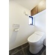 石調のフロアタイルを採用したトイレ。
棚はウォルナットカラーの扉に取り換え、住まい全体の統一感を演出