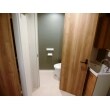 木目のドアを開けると、モスグリーンのアクセント壁が現われるリフォーム後のトイレ。お洒落です。