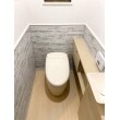 腰壁にTOTOのハイドロセラ・ウォールの積み石柄（グレー）、トイレ本体とキャビネットの明るいベージュが雰囲気を柔らかく、ほっとする優しい空間に。