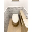 腰壁にTOTOのハイドロセラ・ウォールの積み石柄（グレー）、トイレ本体とキャビネットの明るいベージュが雰囲気を柔らかく、ほっとする優しい空間に。