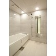 浴室は在来工法のようにタイルを張れるタイプのユニットバスをセレクトしました。清潔感のあるホワイトを基調に、マーブル柄の壁面パネルが高級感を演出しています。フロアにはマットな質感の200角の大型タイルが張られ、ホテルのようなワンランク上の上質な浴室になりました。